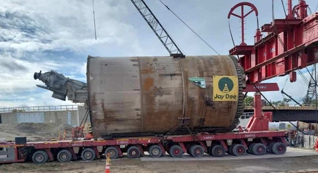 Large tunnel boring machine on long trailer under a crane in preparation for transportation
